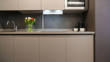 Una cocina moderna con un microondas de acero inoxidable, un horno empotrado y un florero con tulipanes en la encimera.