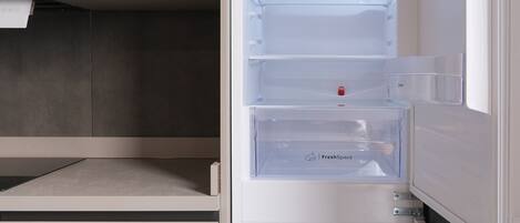 A modern kitchen with a built-in microwave and a white refrigerator with multiple compartments.
