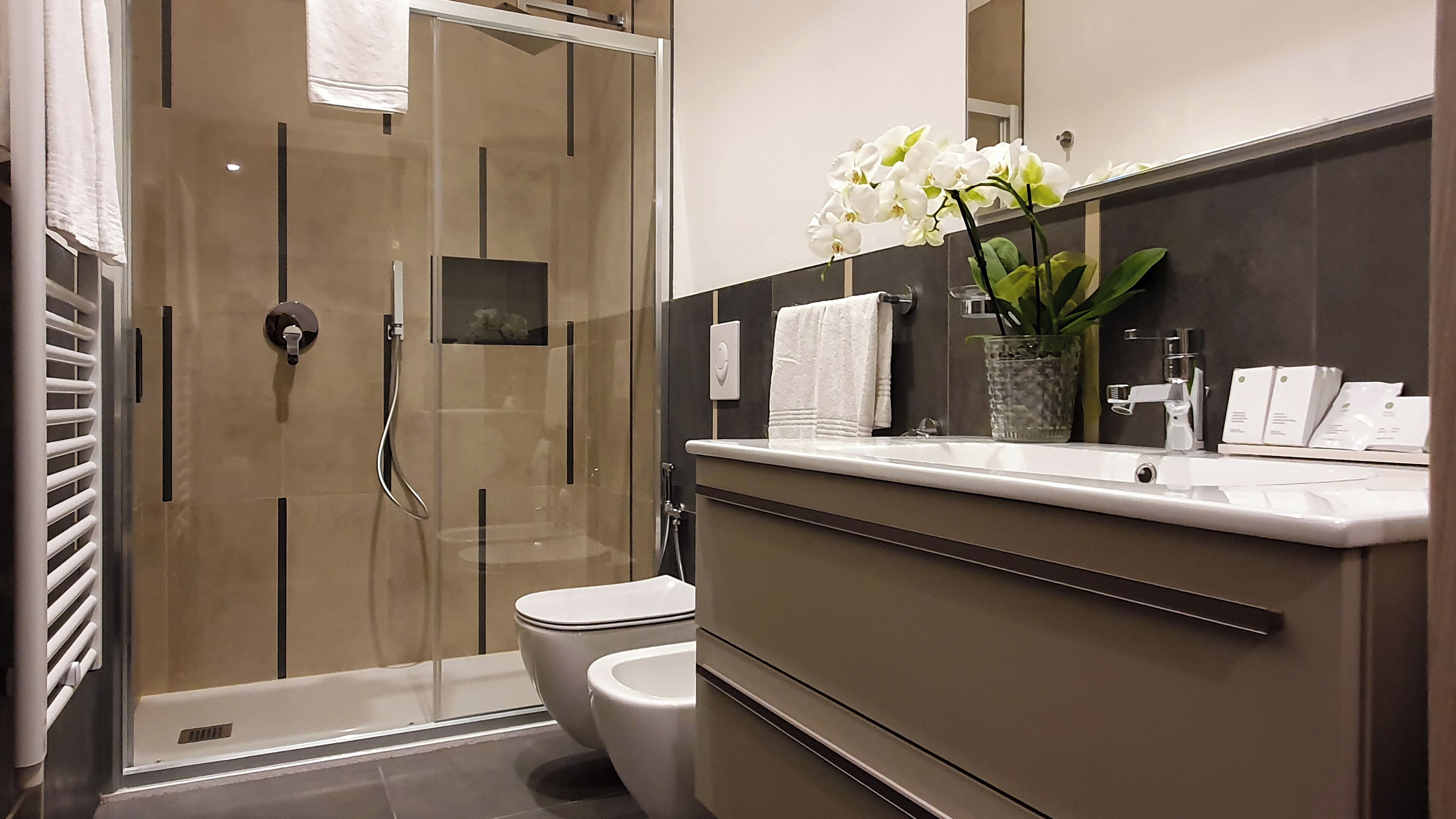 A modern bathroom with a glass-enclosed shower, a toilet, and a vanity with a mirror.
