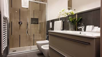 A modern bathroom with a glass-enclosed shower, a toilet, and a vanity with a mirror.