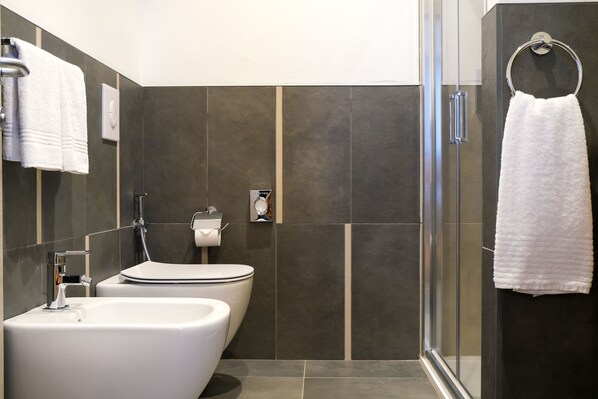 A modern bathroom with a glass shower enclosure, a white sink, and a toilet. - Emerald Green Residence (Caldiero)