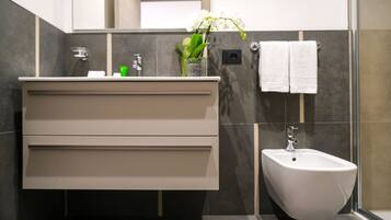 A modern bathroom with a vanity, bidet, and a vase with flowers.