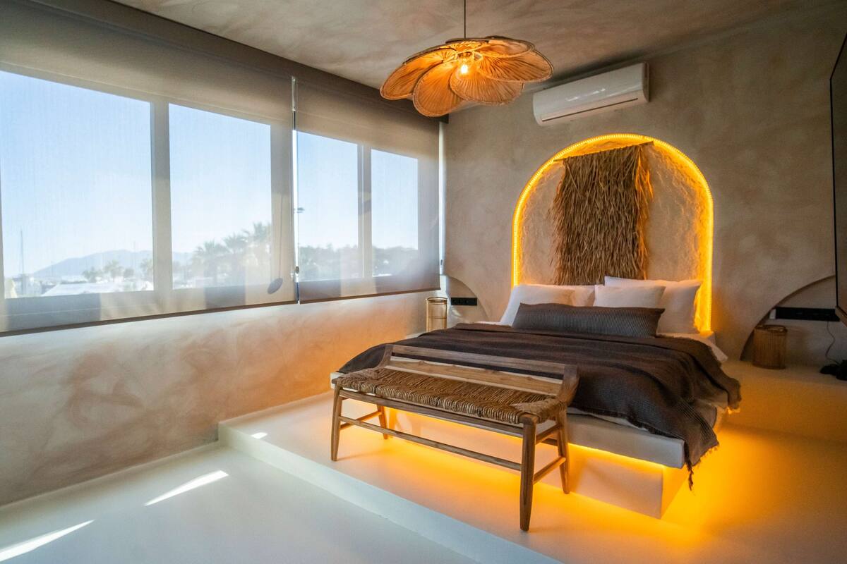 A modern bedroom with a large bed, a bench, and a unique wall feature.