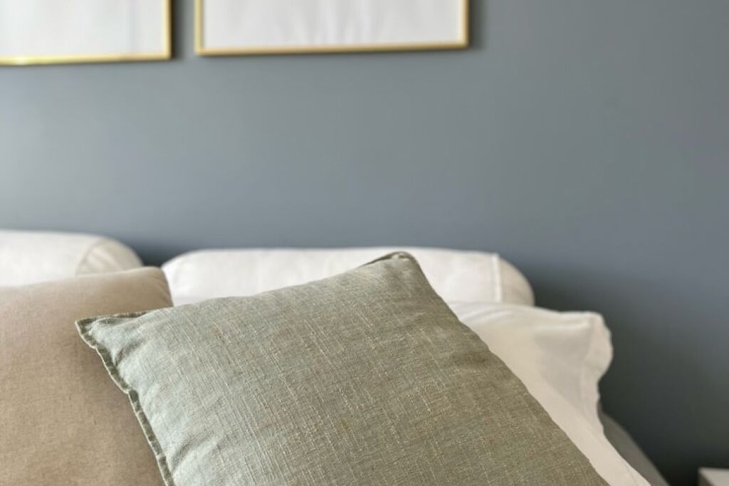 A bed with white bedding and a green pillow.