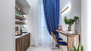 Eine moderne Küche mit Holzausstattung, einer eingebauten Kochinsel und einem blauen Vorhang.