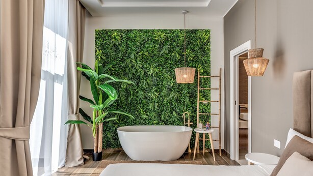 Ein modernes Badezimmer mit einer großen Badewanne, einer grünen Pflanzenwand und einer Holzleiter.