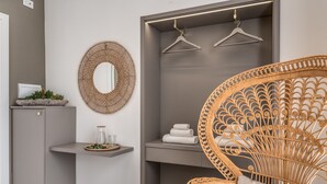 Ein modernes Badezimmer mit grauem Schrank, einem Korbstuhl, einem Spiegel und einem Ablagefach mit Handtüchern.