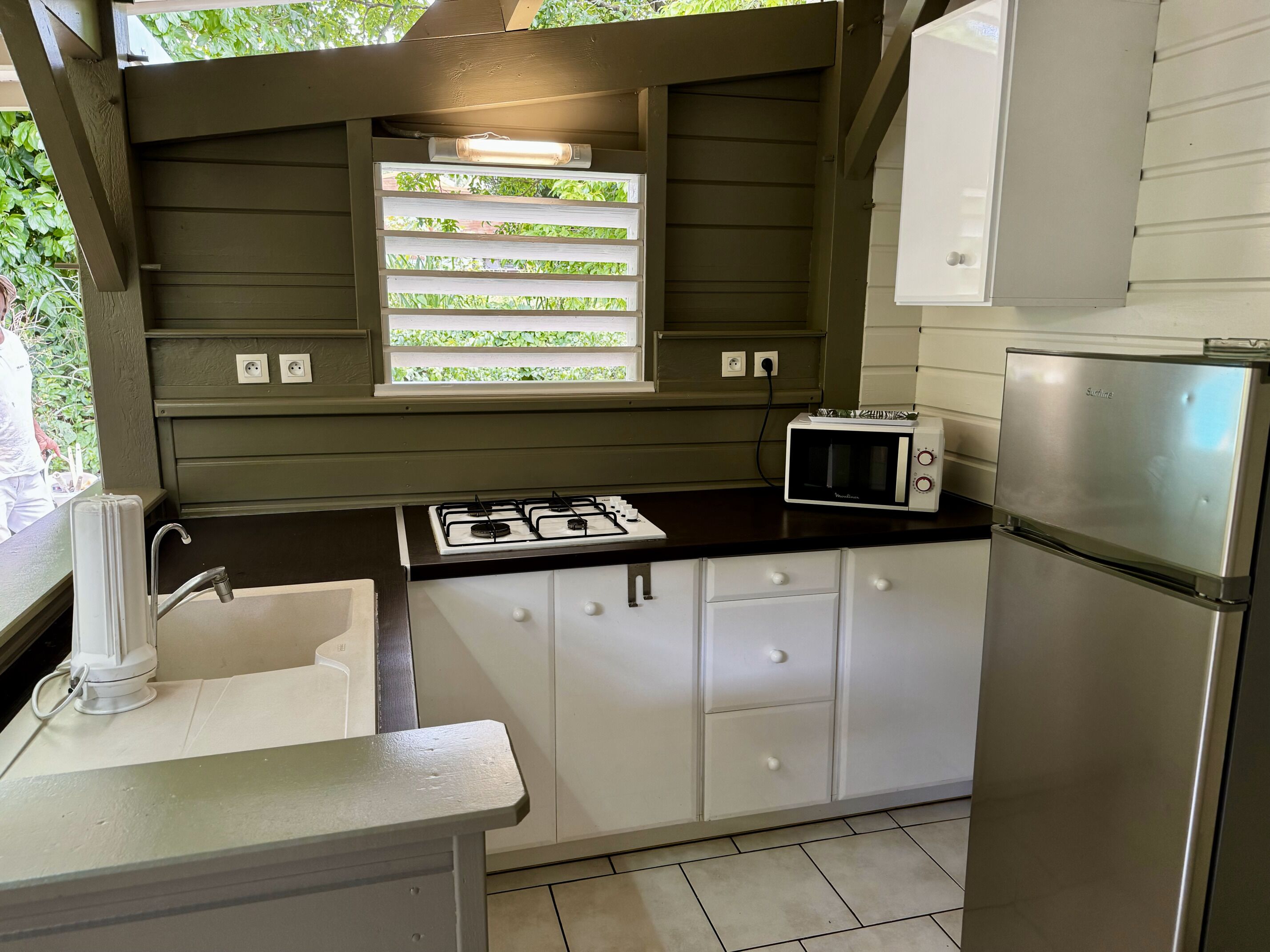 Una cocina compacta con estufa a gas, microondas y refrigerador.