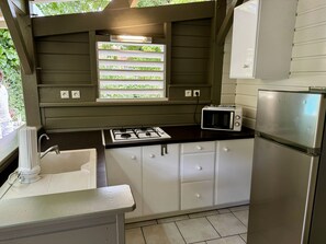 Una cocina compacta con estufa a gas, microondas y refrigerador.