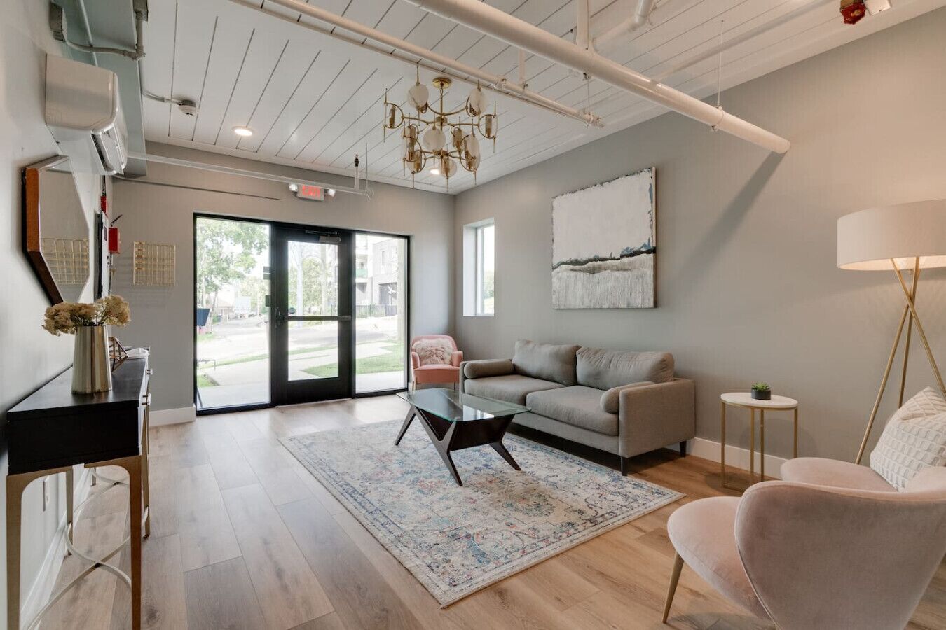 A modern living room with a sofa, armchair, coffee table, and a large window.