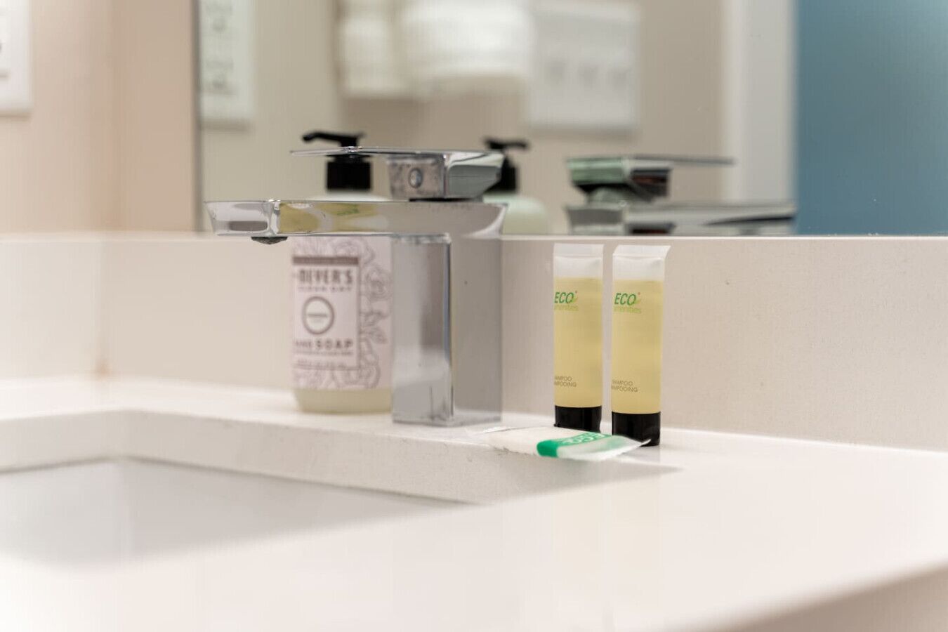 A bathroom sink with a soap dispenser and two shampoo bottles.