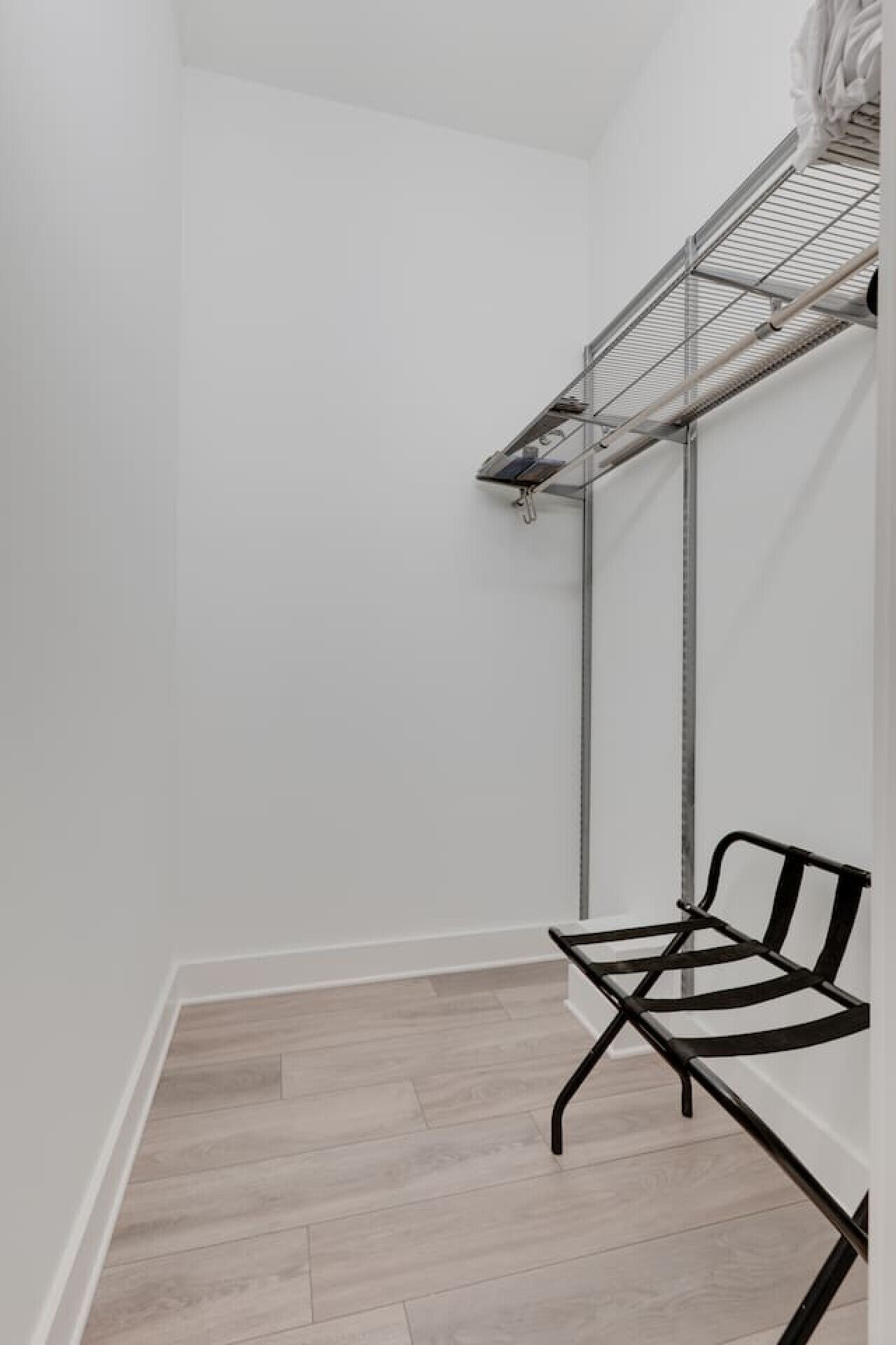A room with a black metal chair, a white wall, and a wooden floor.