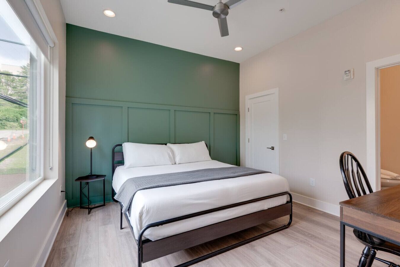 A modern bedroom with a bed, bedside table, and a desk with a chair.