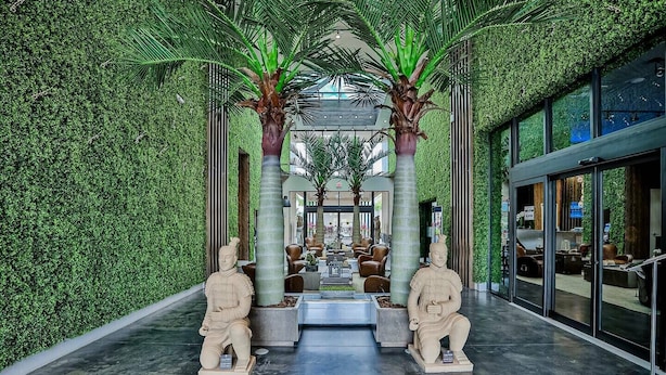 Un hall d’entrée moderne agrémenté d’un mur végétal, de deux statues en pierre et d’un espace salon central.