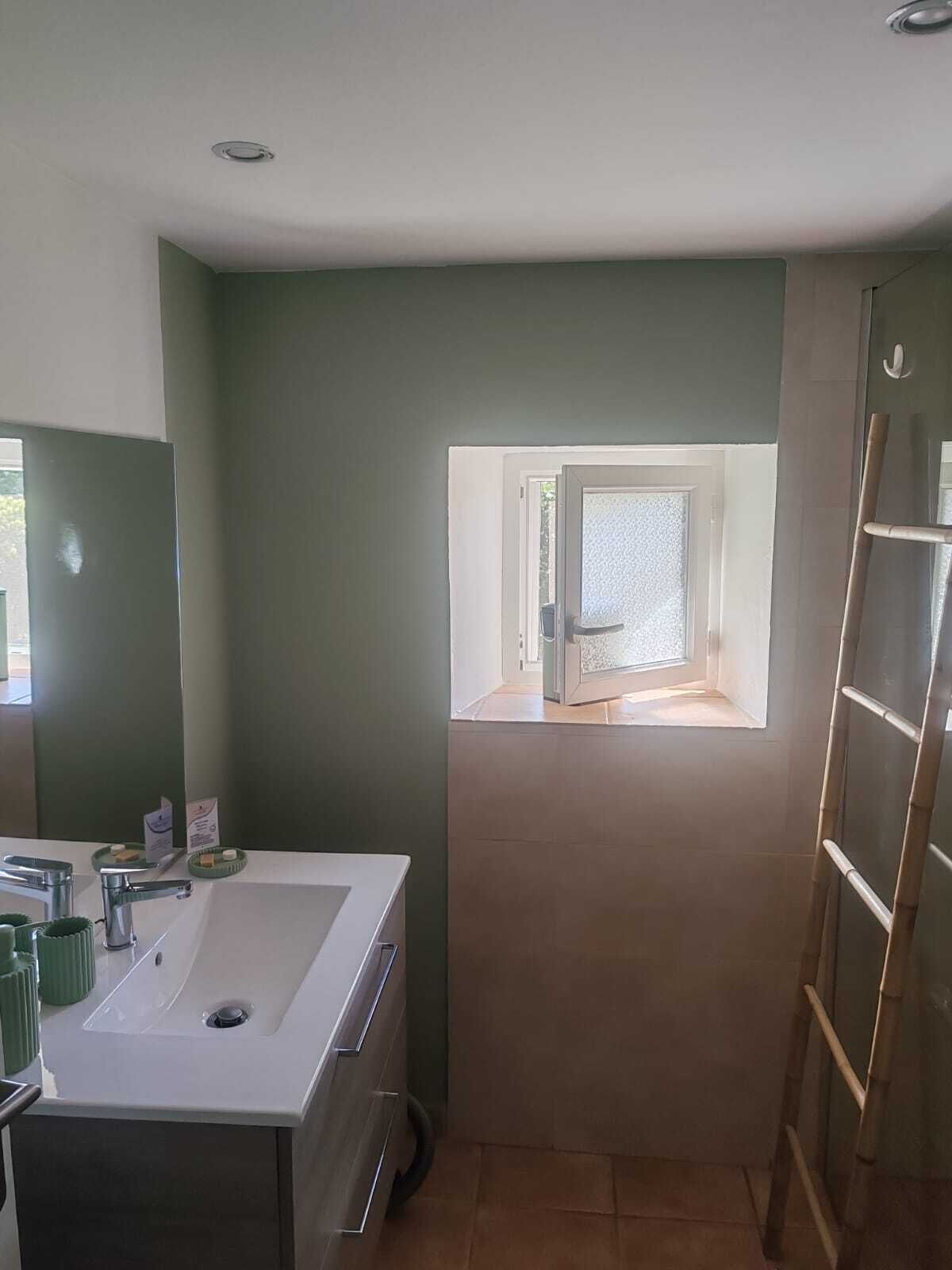 Un bagno con un lavandino bianco, uno specchio, una finestra e una scala.