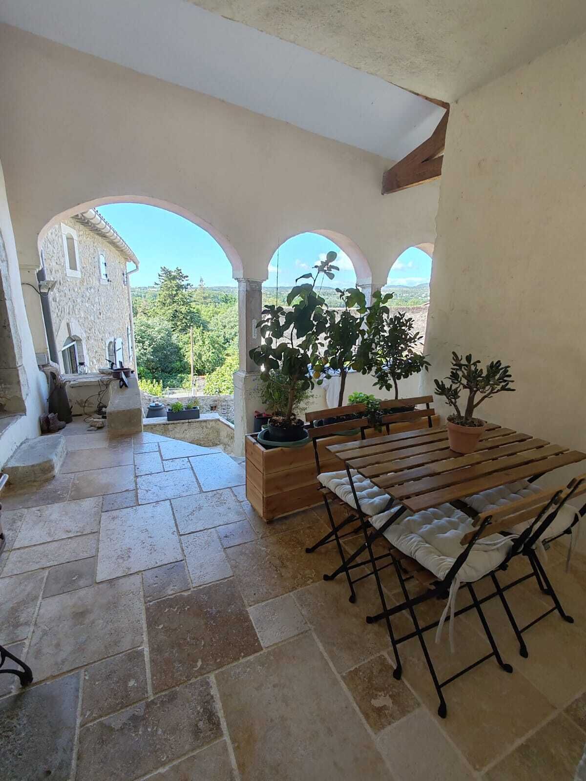 Un patio cubierto con suelo de piedra, muebles de madera y plantas en macetas.
