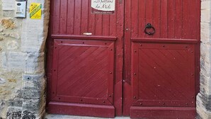 Una puerta de madera roja con un letrero encima que dice "Les pastis An Nid".