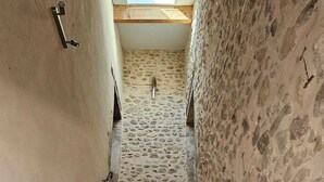 Una estrecha escalera con paredes de piedra y escalones de madera, que conduce a un piso superior.