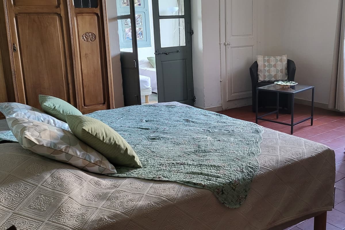Un dormitorio con una cama grande, un armario de madera, una mesita con un plato y una silla.