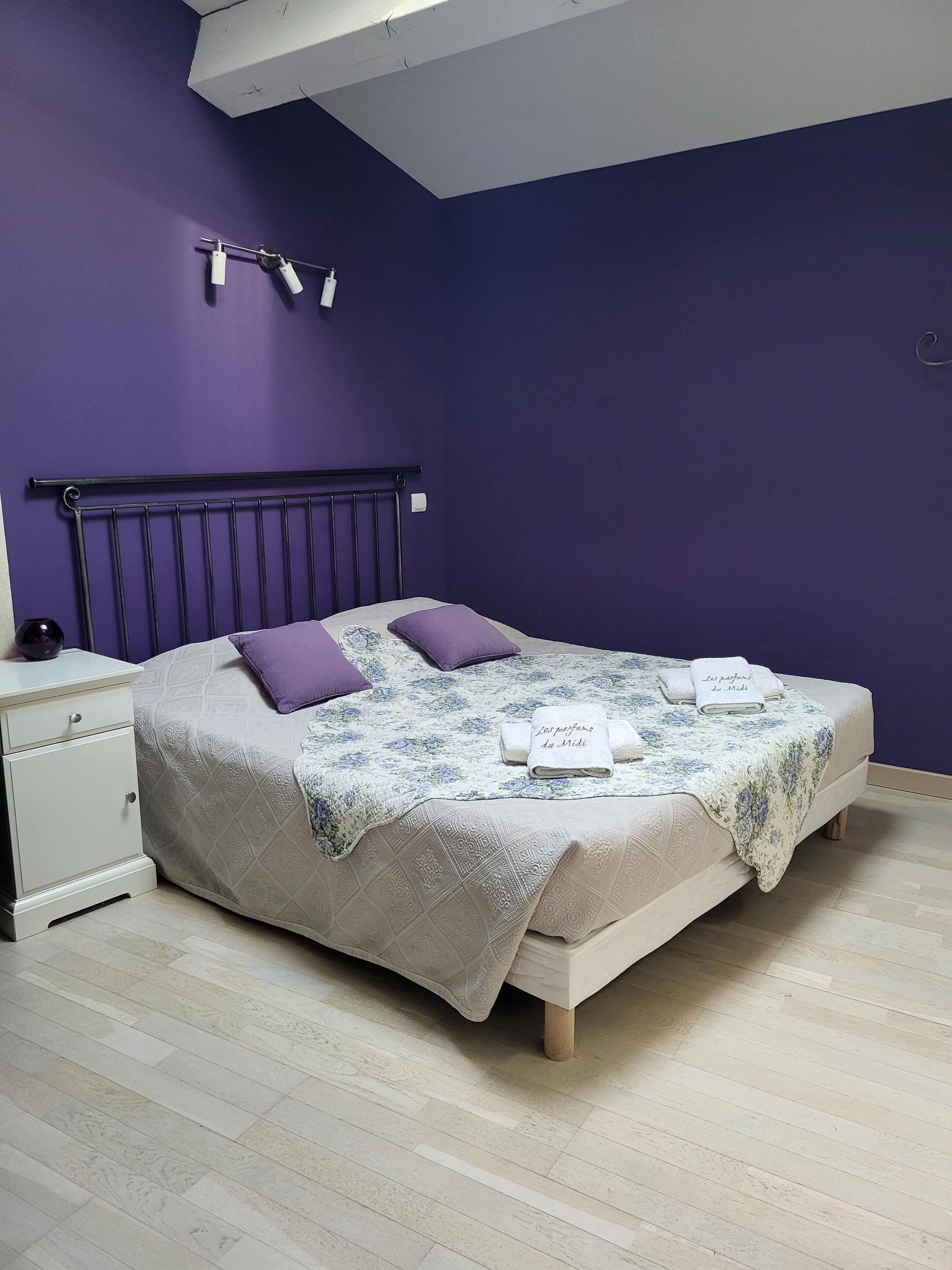 Un dormitorio con cama, mesita de noche y lámpara de techo.