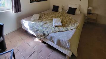 Un dormitorio con una cama, una ventana con cortinas, un cuadro de girasoles y una mesita de noche con una lámpara.