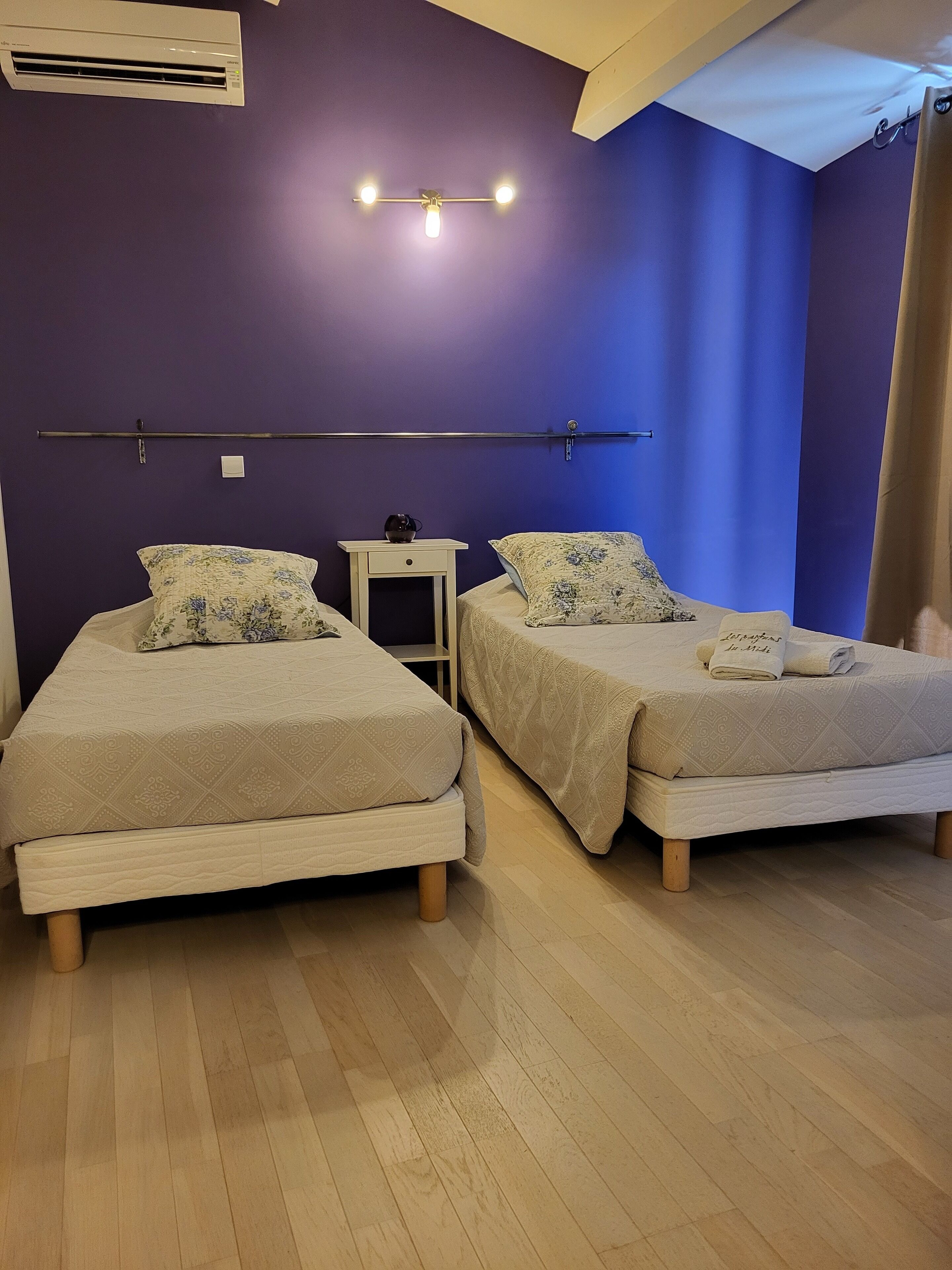 Une chambre avec deux lits, une petite table et un appareil de climatisation.