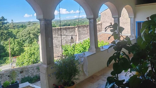 Un espacio al aire libre cubierto con arcos, vistas a la vegetación y un edificio al fondo.