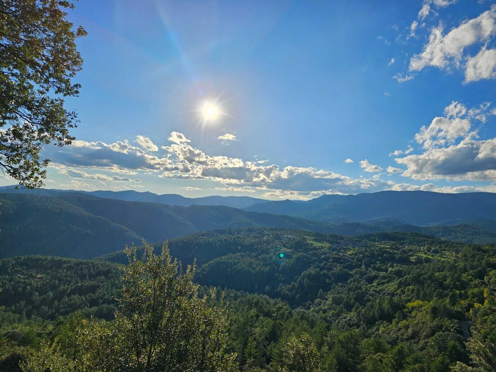 A mountainous landscape with a clear sky and sun shining.