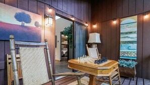 A chessboard set up on a wooden table in a room with wooden walls and a painting of trees. - Rustic Retreat (Hedgesville)
