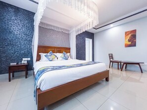 Un dormitorio con una cama grande, una mesita de noche, una silla y un cuadro en la pared.