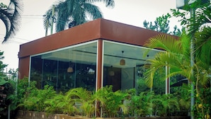 Un edificio moderno con grandes ventanales de vidrio y un jardín vertical de madera con plantas tropicales.