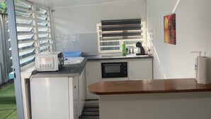 Una cocina compacta equipada con microondas, un refrigerador pequeño y un lavamanos.