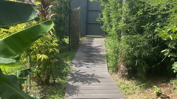Un sendero de madera que conduce a un edificio con techo rojo.