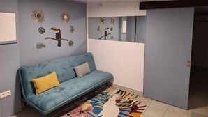 Una habitación con un sofá azul, un tapete colorido y obras de arte en las paredes que incluyen pájaros y hojas.