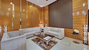 Una sala de estar moderna con un sofá modular, una mesa de centro y un ventanal con persianas.