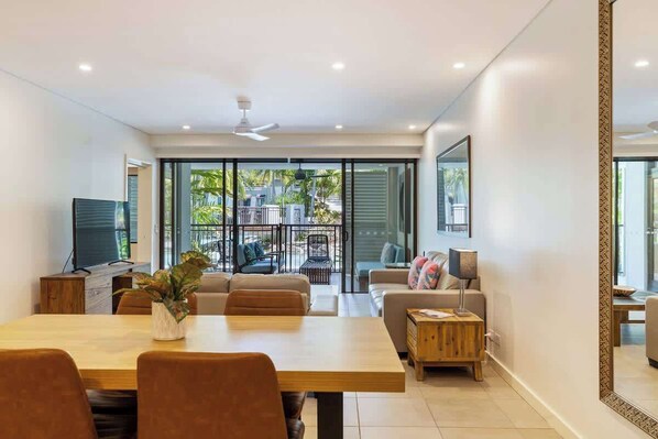 A modern living room with a dining area, a television, and a large window.