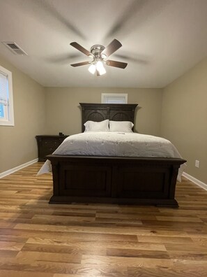 Quarto com cama de madeira, ventoinha no teto e janela.