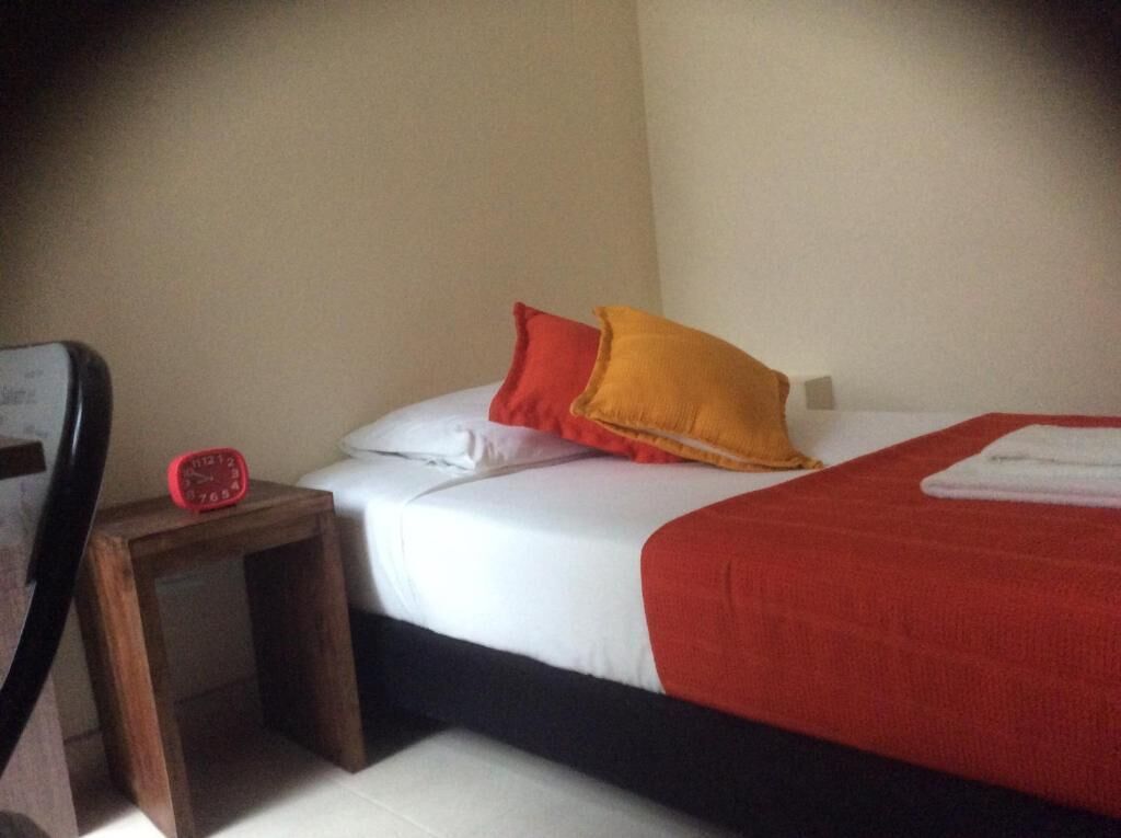 Ein Schlafzimmer mit einem Bett, einem Nachttisch und einem roten Wecker.