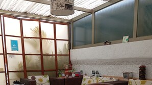 A cozy room with wicker furniture, a patterned floor, and a view through large windows. - The Palma Home (Bogotá)