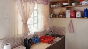 A compact kitchen with a window, wooden ceiling, and a sink. - Lux Suites 2 Bedroom Donholm Bungalow (Nairobi)