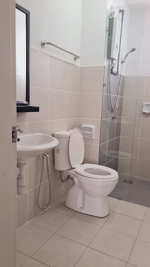 Et badeværelse med toilet, håndvask og bruser.