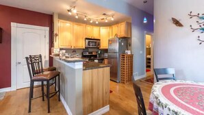 A compact kitchen with wooden cabinets, a central island, a microwave, and a refrigerator. - Private Condo in heart of downtown Golden, CO. (Golden)