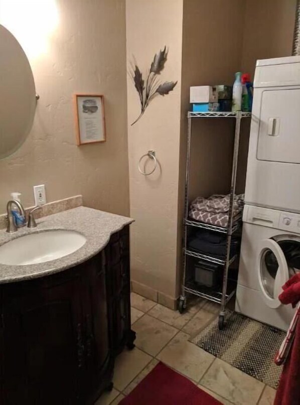 A bathroom with a sink, mirror, towel rack, and a washing machine.