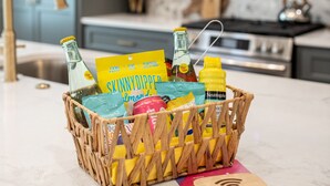 Een keuken met een rieten mand vol verschillende etenswaren en een draadloze oplader op het aanrecht.