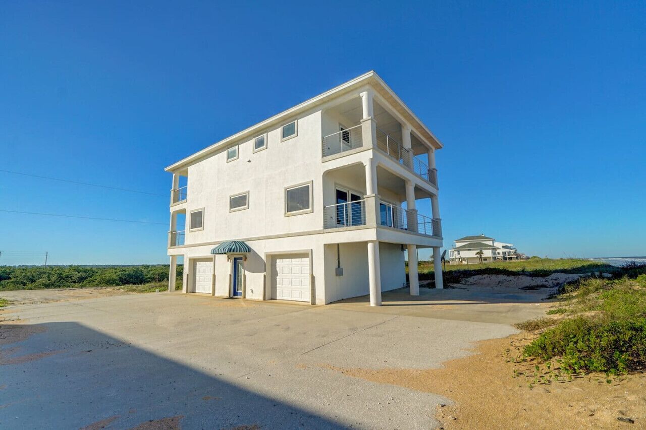 A two-story building with a garage, a covered entrance, and a balcony.