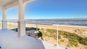 Un balcon fermé offrant une vue sur la plage et l’océan.