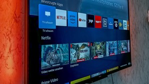A flat-screen TV mounted on a textured wall displaying a digital interface with app icons and content thumbnails.