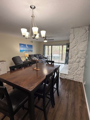 A dining area with a wooden table, chairs, a ceiling fan, and a view of the outdoors.