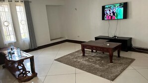 A living room with a TV, a coffee table, and a TV stand. - Lux Suites Marrakech Apartments (Mombasa)