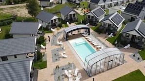 A residential complex with multiple houses, a swimming pool, and a covered outdoor area with lounge chairs. - Holiday homes with air conditioning, pool, jacuzzi (Jaroslawiec)